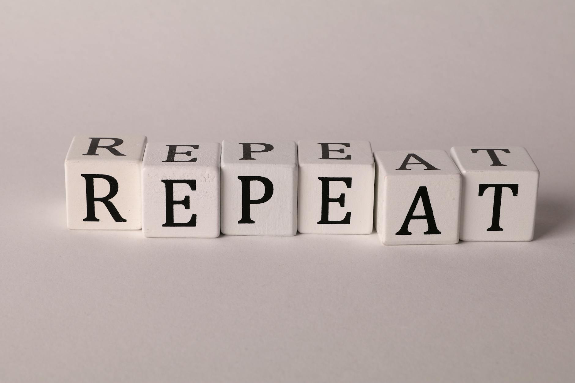 photo of cubes with letters forming the word repeat