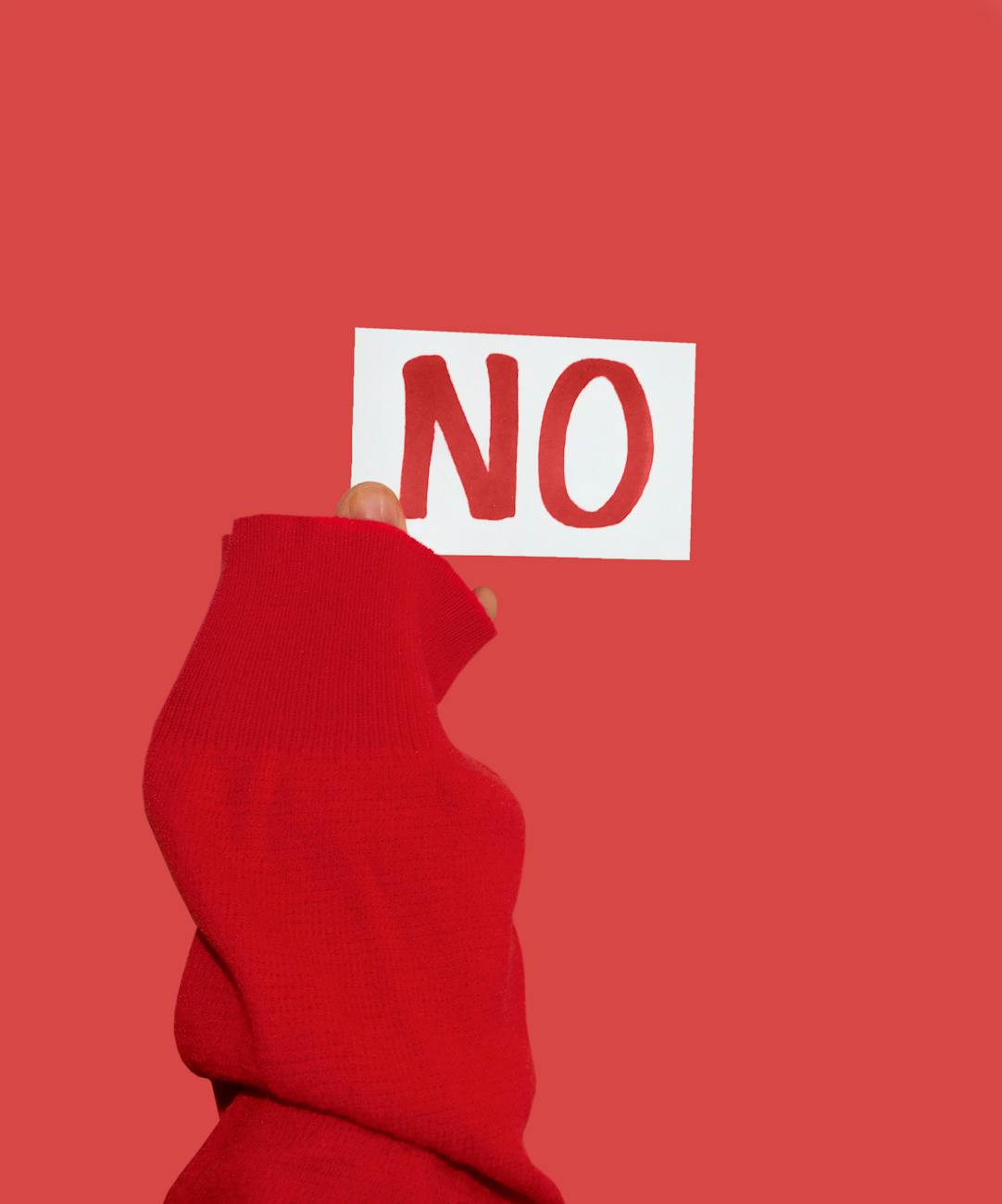 a person in red long sleeve shirt holding a no sign on red surface